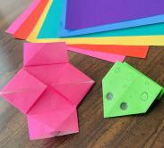 Pink origami lantern and green origami frog with colorful origami paper in the background