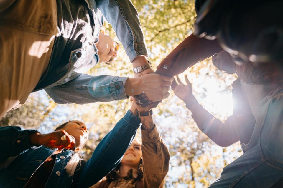 various people joining hands in circle