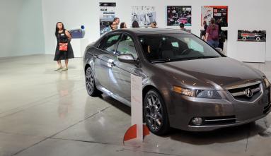 people in gallery looking at car related exhibition