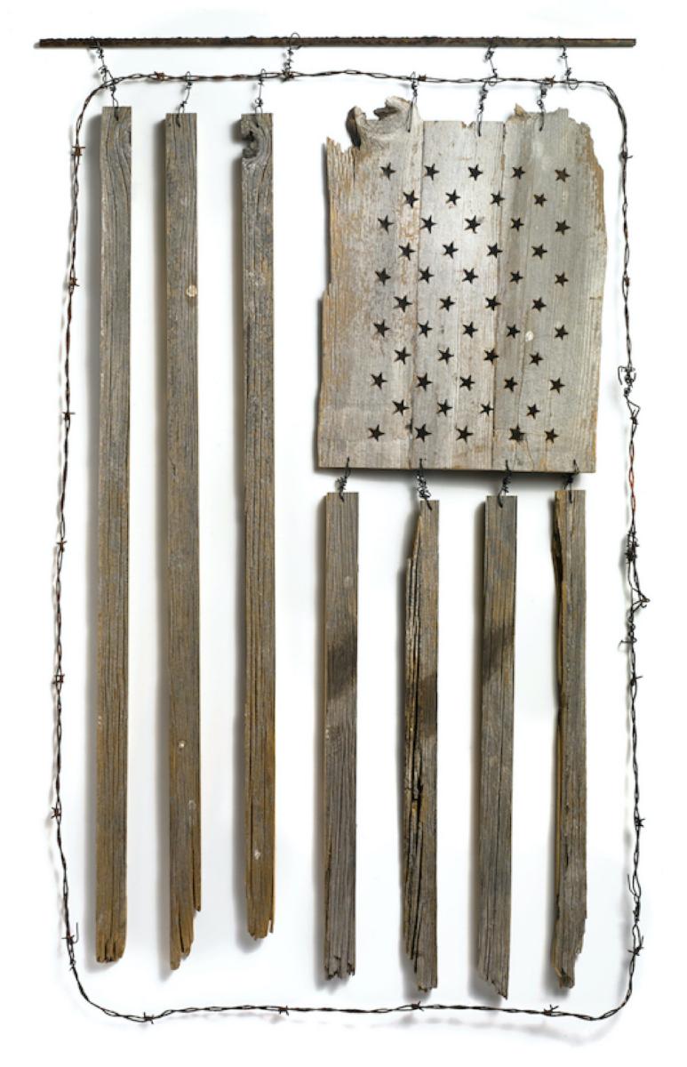 artwork featuring an American flag made of scrap wood and barbed wire