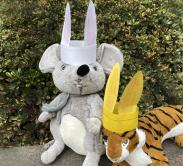 Rabbit ears made of paper on top of heads of stuffed animal mouse and tiger.