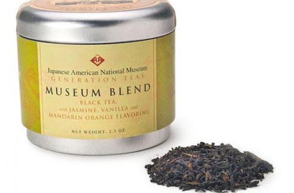 tin canister with green label that says "Japanese American National Museum Generation Teas Museum Blend" and a small scoop of tea leaves sitting next to it