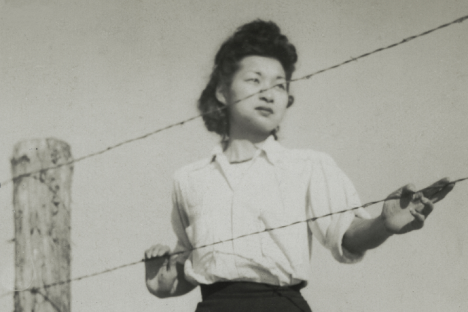a young woman behind barbed wire