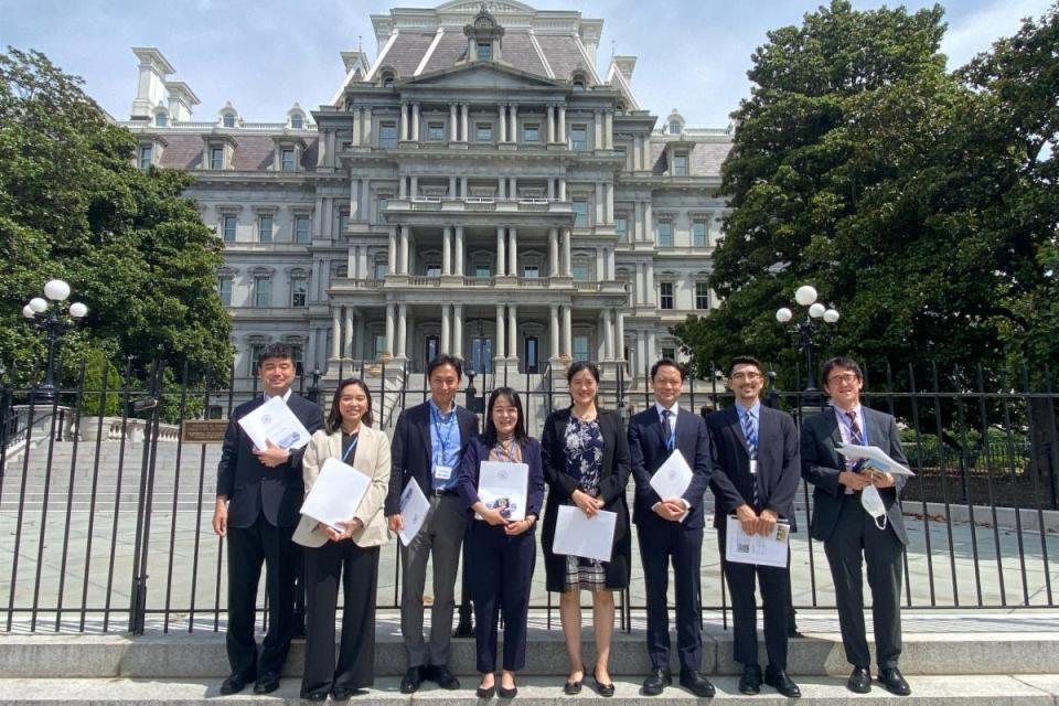 8 people holding certificates standing in front on the Eisenhower building