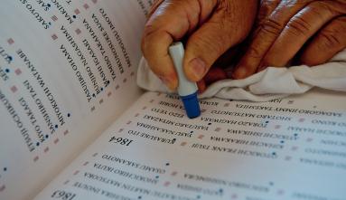 a person's hand stamping a dot under a name in a book